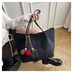 Detail of matte black tote bag with bohemian colorful tassel charm and wooden beads
