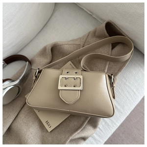 Détail du sac à main beige en similicuir avec boucle argentée sur fond en laine