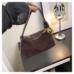 Detail of vintage brown suede bag with prominent gold chain strap and zipper closure
