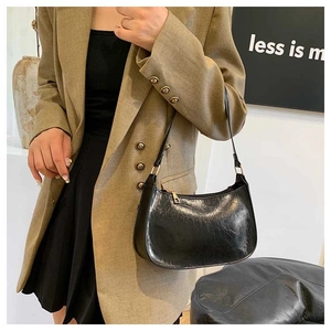 Detail of black crescent shoulder bag with vintage crinkle texture and gold hardware