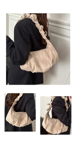 Détail d'un sac dumpling plissé beige avec large bandoulière à volants en tissu de qualité