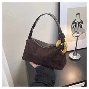 Detail of dark brown suede Boston bag featuring oversized gold chain link hardware