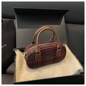 Detail of red plaid woolen handbag with brown leather handles in a premium gift box