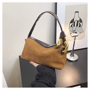Detail of brown frosted suede handbag featuring a bold gold chain link accent and zipper