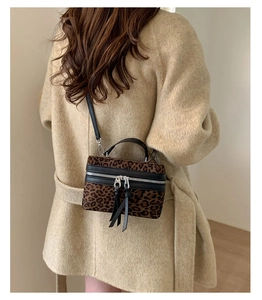 Détail d'une femme en manteau beige portant un sac bandoulière léopard de forme boîte