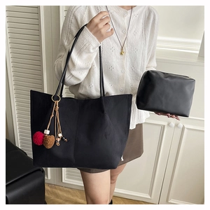 Detail of black matte tote bag set with fuzzy charms against a white shutter background