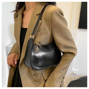 Detail of black wax texture hobo bag with gold hardware on a shoulder
