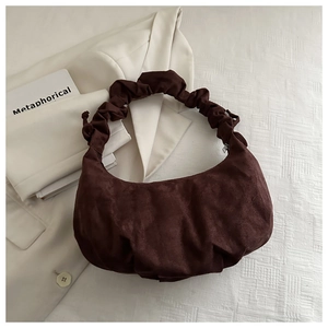 Détail d'un sac hobo en daim marron foncé avec une poignée plissée effet nuage