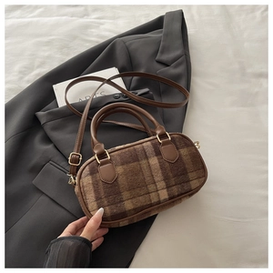 Detail of brown plaid texture with plush material and gold hardware on tote bag
