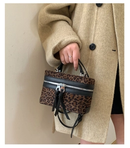 Détail du sac seau léopard avec bordures en cuir noir et fermetures éclair à glands