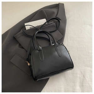 Top view of a black PU leather Boston bag on a grey blazer, showing handles and strap