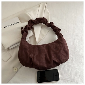 Détail du sac à main froncé en daim marron foncé comparé à la taille d'un smartphone