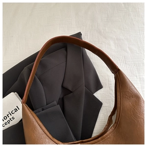 Vue de dessus d'un sac demi-lune en cuir marron texturé avec un blazer gris