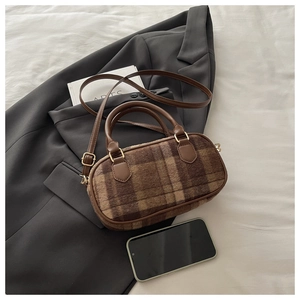 Detail of checkered plush Boston bag with leather handles and gold-tone hardware on a blazer