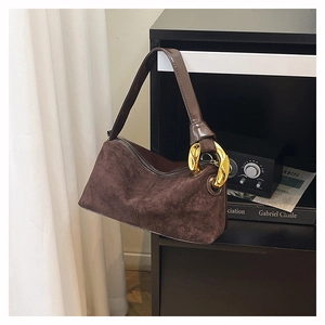 Detail of dark brown suede shoulder bag with a large gold metal buckle and leather strap