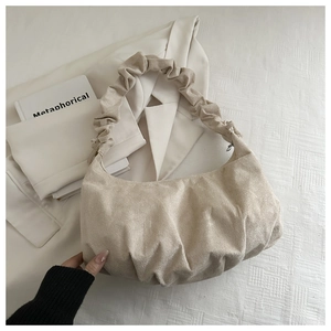Détail du sac dumpling beige plissé avec anse froncée et finition à texture perlée brillante