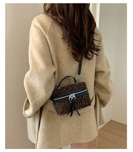 Détail du sac seau léopard porté en bandoulière avec sangle noire sur le dos du mannequin