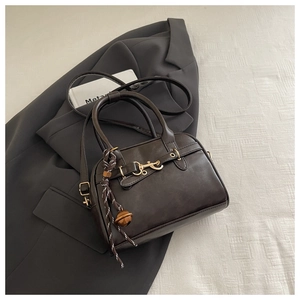 Detail of dark brown leather handbag with gold horsebit buckle and woven charm