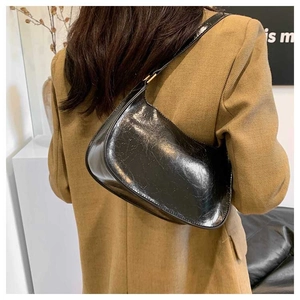 Detail view of the black glossy underarm bag with adjustable shoulder strap