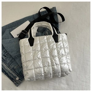 Détail d'un sac cabas matelassé blanc avec finition brillante et anses noires