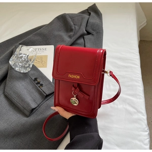 Détail du petit sac bandoulière rouge avec texte FASHION jaune et pendentif en métal rond