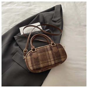 Detailed view of brown plaid plush barrel bag on grey blazer with adjustable leather strap