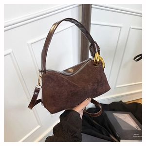 Close-up of retro brown suede handbag featuring sleek gold hardware and decorative metal ring