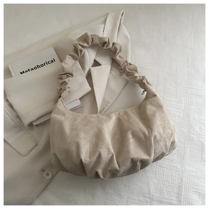 Gros plan du sac beige plissé avec bandoulière scrunchie sur texture blanche pure