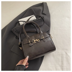 Detail of vintage coffee brown PU leather shell bag with gold horsebit buckle and handles