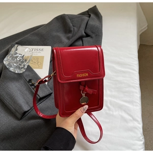 Détail du petit sac rouge carré avec nœud décoratif et logo Fashion doré gravé