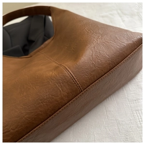 Détail d'un sac cabas vintage marron foncé montrant la texture du similicuir et les coutures