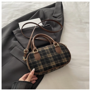Detailed close-up of brown checkered tweed handbag with leather handle and golden buckle