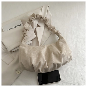 Détail d'un sac hobo plissé crème en tissu texturé avec fermeture éclair métallique