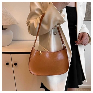 Brown leather half-moon underarm bag with gold zipper and minimalist texture detail