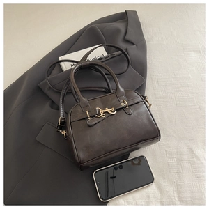 Detailed flat lay of a vintage brown shell bag with gold horsebit hardware on a blazer