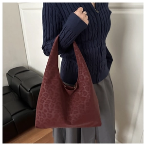 Detail of burgundy leopard print hobo bag with unique knotted handle on shoulder