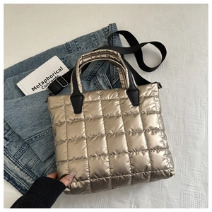 Détail du sac cabas matelassé doré champagne avec une bandoulière noire réglable
