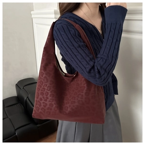 Detail of dark burgundy tote bag with leopard emboss pattern and matte finish