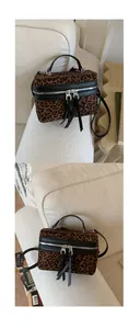 Détail du sac boîte léopard avec double fermeture éclair et pompons en cuir noir