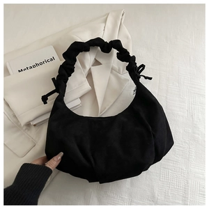 Gros plan sur la poignée froncée noire et le nœud coulissant du sac hobo