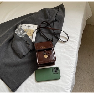 Détail d'un sac pour téléphone en cuir marron foncé avec inscription FASHION au dos