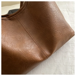 Gros plan sur la texture du cuir grainé marron foncé et surpiqûres du cabas