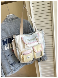 Close-up of a multi-pocket tote bag with blue and yellow panels and a clear PVC window