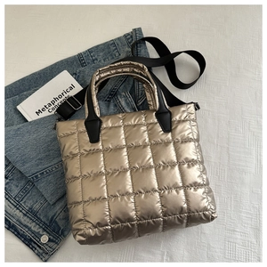 Détail du sac matelassé or champagne avec bandoulière noire et texture en nylon rembourrée