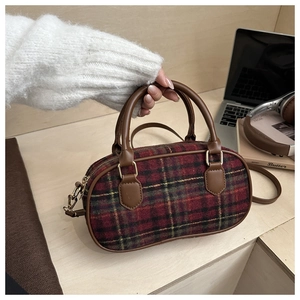 Detail of British plaid mini Boston bag with brown leather handles on a desktop