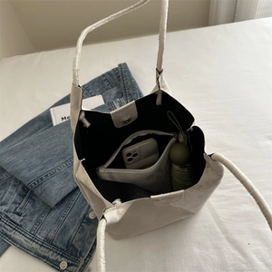 Spacious beige suede bucket bag showing internal capacity with phone and umbrella