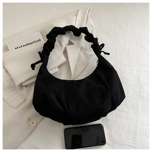 Détail du sac lune noir en daim avec bandoulière froncée et nœud décoratif