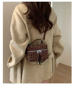 Détail du sac boîte léopard avec doubles zips métalliques et longs glands en cuir