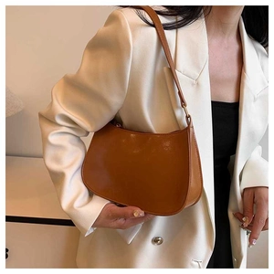 Close-up of brown glossy oil-waxed leather shoulder bag on a model in white blazer
