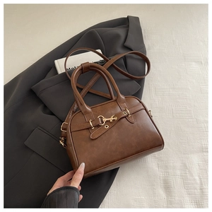 Detail of retro caramel brown boston bag with metal bar clasp on grey suit fabric
